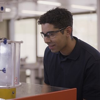 Person mit Schutzbrille schaut in ein Gerät