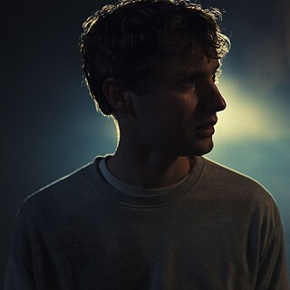 A young man out in the cold. A car pulls up behind him.