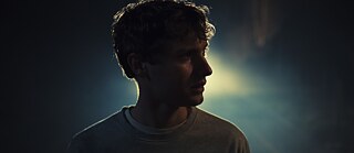 A young man out in the cold. A car pulls up behind him.