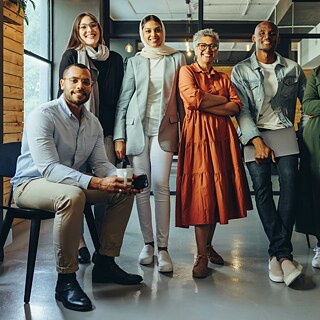 Lächelnde Menschen stehen nebeneinander und schauen in die Kamera