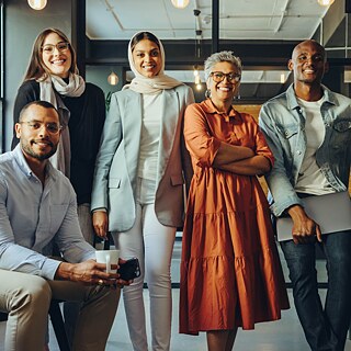 Lächelnde Menschen stehen nebeneinander und schauen in die Kamera