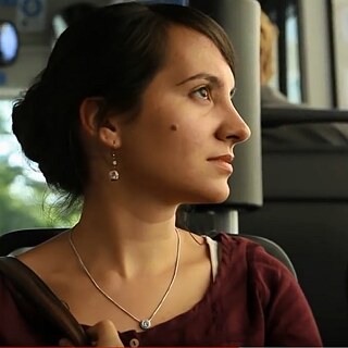  Die junge Frau Nevin sitzt im Bus und sieht aus dem Fenster.