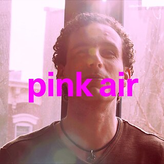 Person mit lockigem Haar, die in einem rosa gefärbten Licht sitzt. Über das Bild ist in großen, kräftigen, pinkfarbenen Buchstaben der Text „pink air“ geschrieben.