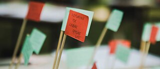 Rohelised ja punased paberlipud. Ühel lipul on inglise keeles kirjutatud „Motivation for getting offline life” (Motivatsioon offline-elu jaoks). 