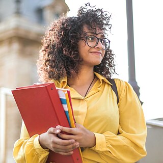 Eine junge Frau mit Büchern auf dem Arm