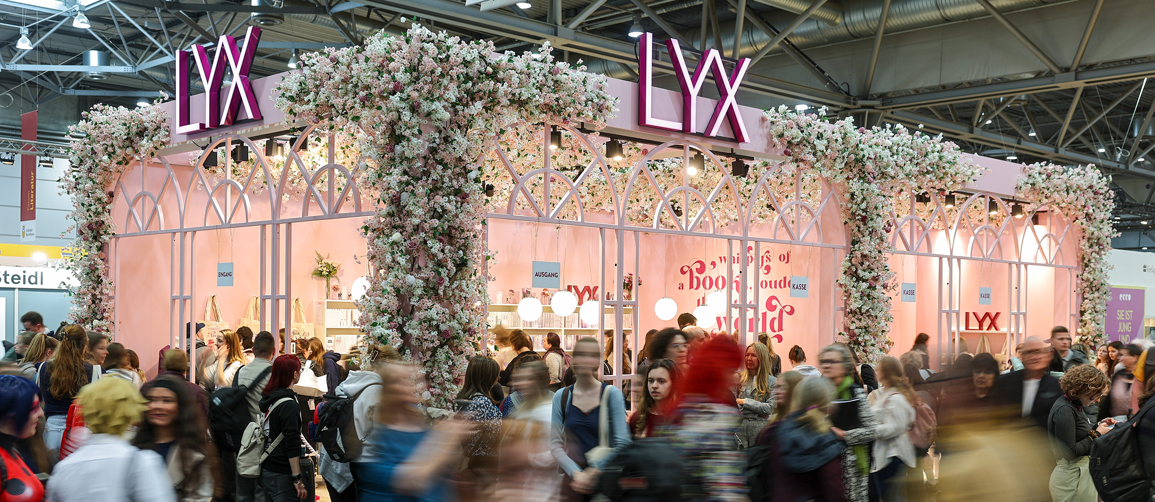 Zahlreiche Menschen passieren den zartrosanen Stand von LYX auf der Leipziger Buchmesse 2025.