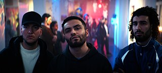 Kenan (Aram Arami) und seine Freunde Sascha (Patrick Phul) und Momo (Fatih Hatipoğlu) schauen irritiert nach vorne.