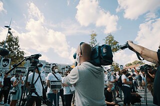 Reporter und Fernsehteams stehen am Jahrestag bei der Gedenkveranstaltung in Hanau.