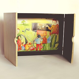 Los presentadores de Kamishibai cuentan historias con textos breves sobre imágenes cambiantes, que se introducen en un escenario similar al de un escenario. Los textos e imágenes están especialmente desarrollados para esta forma narrativa.ildern, die in einen bühnenähnlichen Rahmen geschoben werden. Die Texte und Bilder werden eigens für diese Erzählform erarbeitet.