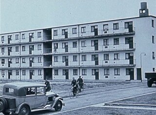 Melnbalts filmas kadrs: dzīva iela ar Bauhaus blokiem fonā