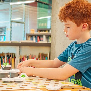 Foto eines Jungs, der in der Bibliothek sitzt und ein Brettspiel spielt