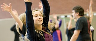 En ung jente strekker armene opp i luften.