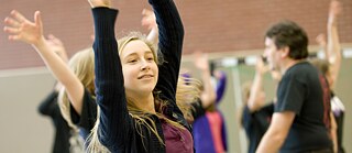 En ung jente strekker armene opp i luften.