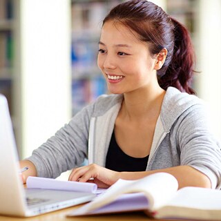 Eine Lehrerin arbeitet am Laptop in der Bibliothek.