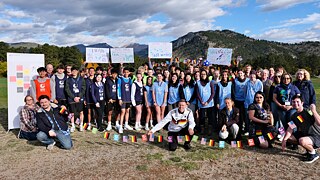A group of teenagers in soccer uniforms posing for a group photo on the lawn