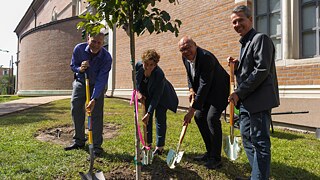 Brent Moon, Kathleen Canning, Johannes Ebert, and Leonhard Emmerling each hold a shovel as they plant an oak tree into the ground.