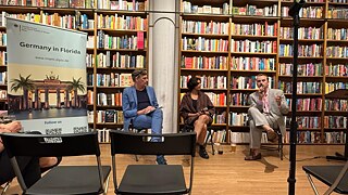 Sonali Beher and Iven Yorick Fenker together with Oliver Gorf in front of a large bookshelf during a reading