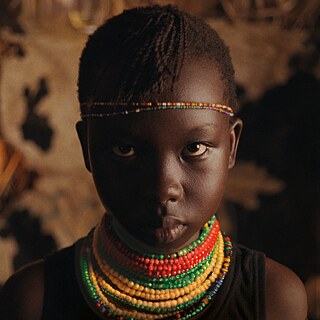 Close up of a brown skinned girl with beads around her neck looking defiant
