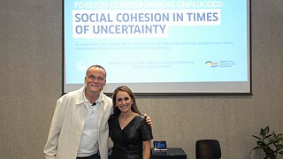 Vladimir Balzer und Celeste Diaz Schurmann stehen vor einer PowerPoint-Präsentation.