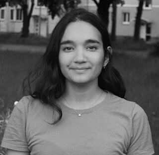 Nesta imagem a preto e branco, está retratada a artista Inês Abreu. Ela olha para a câmara e, ao fundo, vê-se um prado e árvores. 