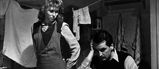 A man and woman in a small space with laundry in the background