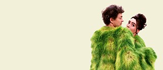 A couple in a green costume on a beige background