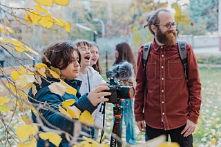 Zwei Jungen entdecken zusammen mit einem Erwachsenen wie eine Kamera funktioniert.