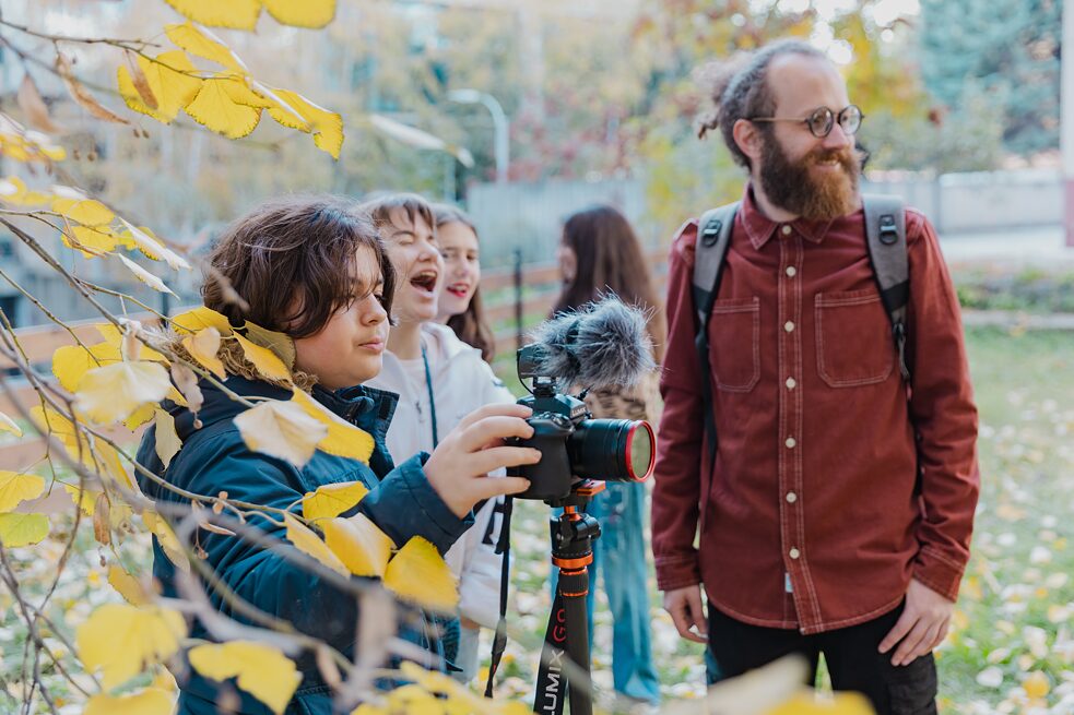 Zwei Jungen entdecken zusammen mit einem Erwachsenen wie eine Kamera funktioniert.
