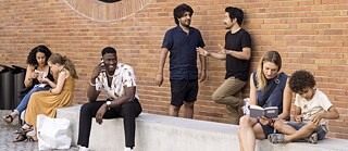 Menschen sitzen und stehen vor einem Gebäude