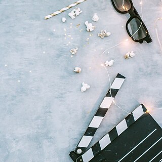 Abstraktní pozadí na téma kino, s pohledem na 3D brýle, popcorn, brčko a filmovou klapku.