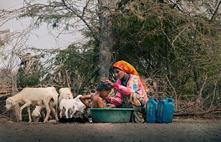 الساحل الغربي - اليمن; حياة على الساحل: أم مازن تحمم طفلها داخل حوض. ستفاد من الماء الذي تم الاغتسال به لأغراض الحمام أو كمياه شرب للمواشي.