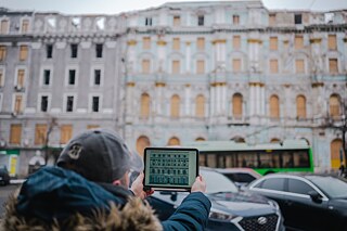Max zeigt auf seinem Tablet einen Entwurf für die Restaurierung eines historischen Gebäudes im Herzen von Charkiw.