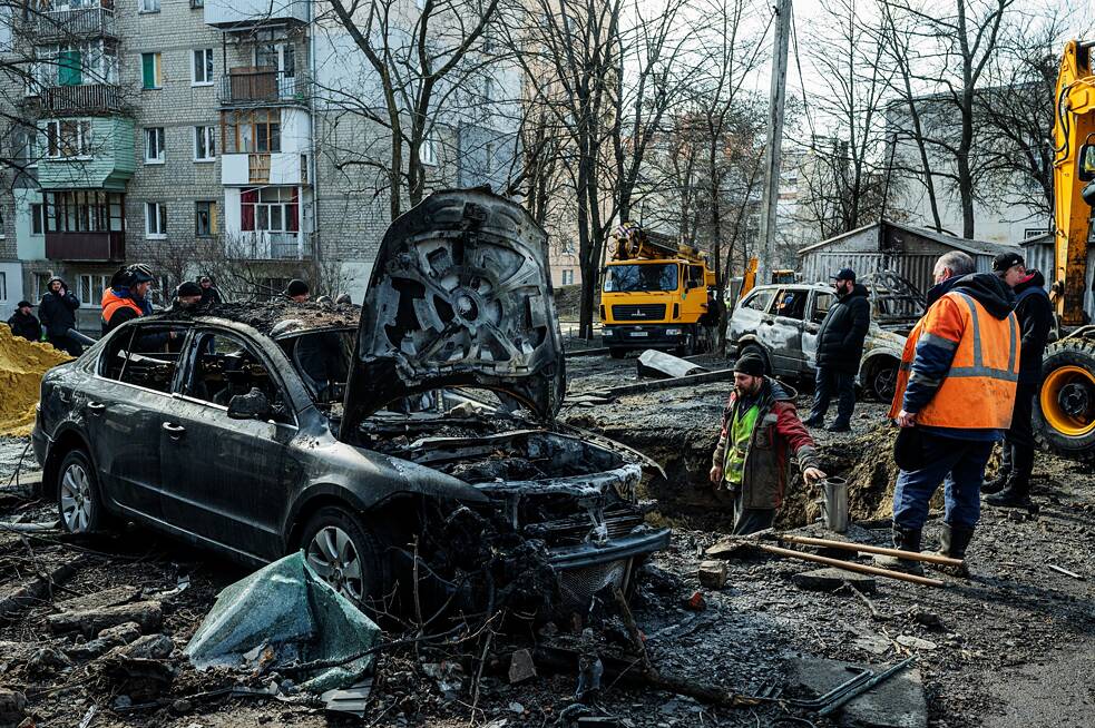 Mitarbeiter des kommunalen Dienstes säubern den Hof eines Mehrfamilienhauses nach einem nächtlichen Angriff.