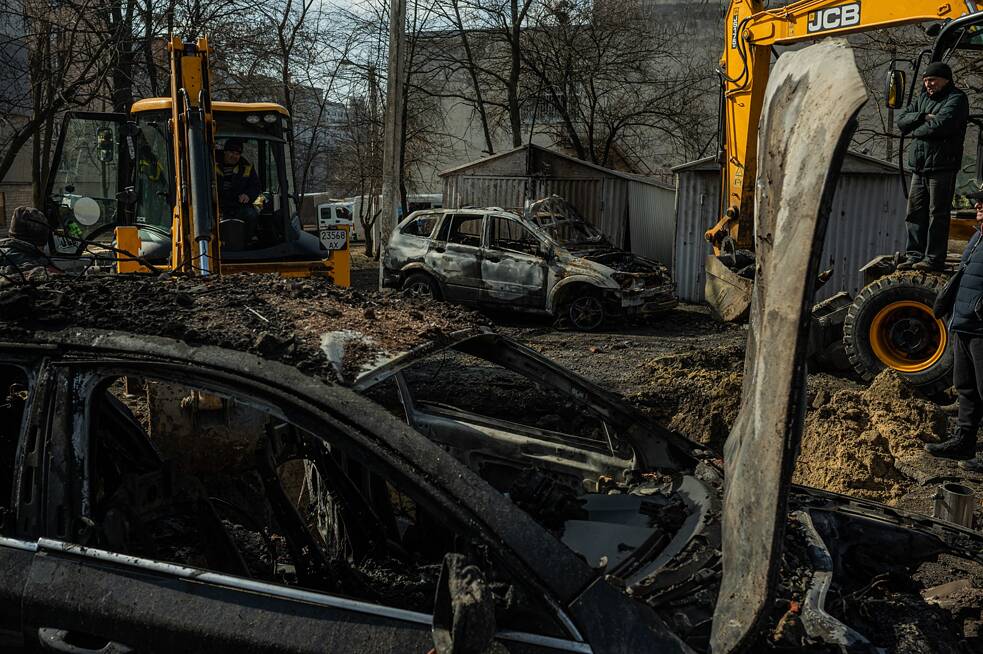 Mitarbeiter des kommunalen Dienstes säubern den Hof eines Mehrfamilienhauses nach einem nächtlichen Angriff.