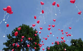 Heart-shaped balloons with cards bearing good wishes for the bride and groom fly up into the sky.