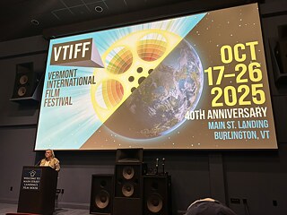 Karin Oehlenschläger behind a podium with a film festival banner in the background