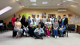 Всі учасники стоять або сидять в конференц залі