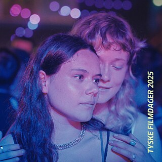 Zwei junge Frauen stehen eng beieinander in einer Umgebung mit bunten Lichtern, vermutlich auf einer Party oder Tanzfläche. 