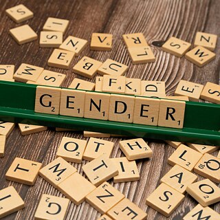 Das Wort "Gender" aus Scrabble-Spielsteinen auf einem Tisch. 