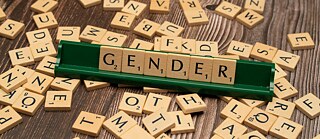 Das Wort "Gender" aus Scrabble-Spielsteinen auf einem Tisch. 