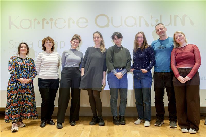 Acht Personen stehen nebeneinander vor einer Leinwand mit der Projektion „Karriere Quantum“ und schauen in die Kamera. Es ist ein Team-Gruppenfoto der Mitarbeitenden des TüftelLab, des Goethe-Instituts Sofia, Dublin und Madrid. 
