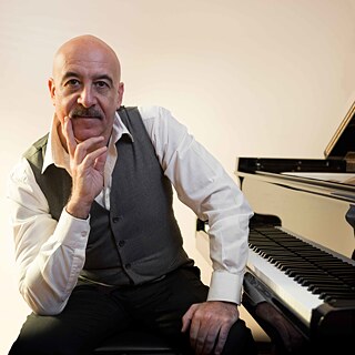 Porträt des Musikers Alessandro Bonanno, der neben dem Klavier sitzt