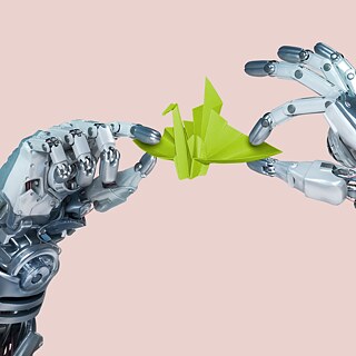 Robothänder håller en grön fågel vikad av papper.