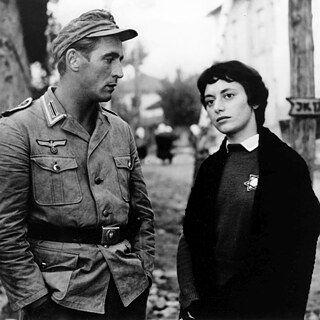 A man in a German uniform and a woman with short dark hair and a Star of David on her clothing stand next to each other in the picture. 