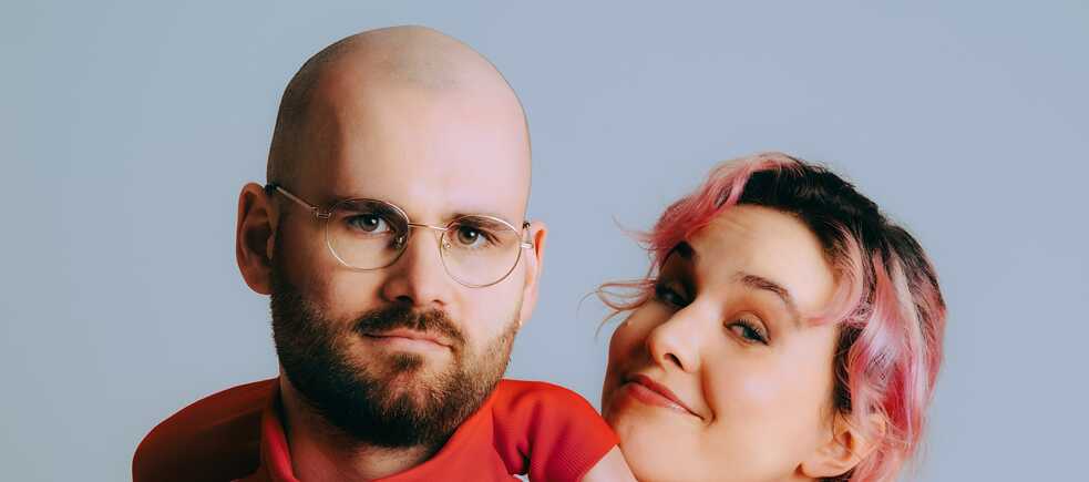 Das Duo vor einer weißen Wand.