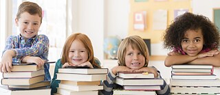 Kinder mit Bücherstapeln