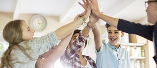 Schüler klatschen im Klassenzimmer die Hände gegeneinander.