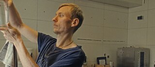 A man holding a glass to see if it's clean. Key image for 'Soldiers of Light' a film at Antenna Festival