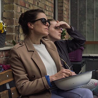 Ausschnitt aus Alle reden übers Wetter: Zwei Frauen sitzen im Garten an einem Tisch und blicken in die Ferne.