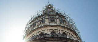 A parliamentary building under renovation. The sun is shining on it.